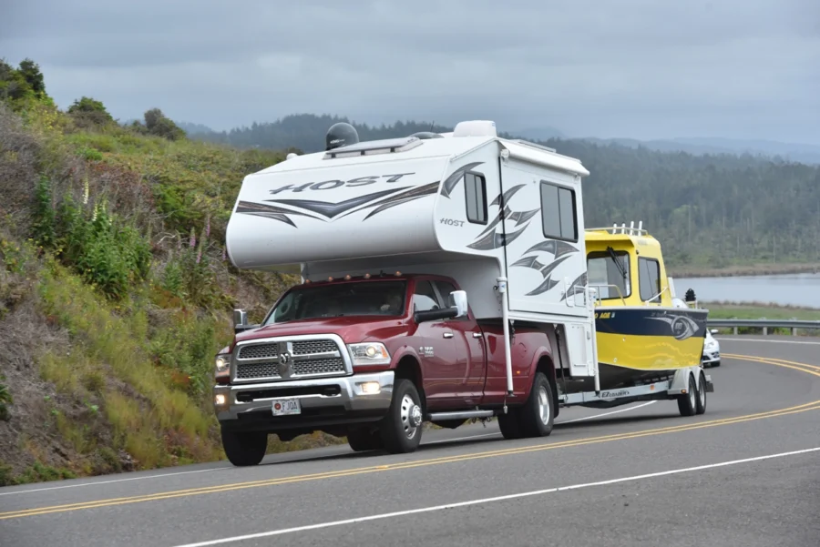 Truck with a camper towing a boat.