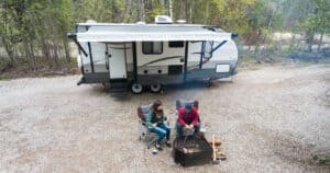 A couple sitting in front of their brand new travel trailer.