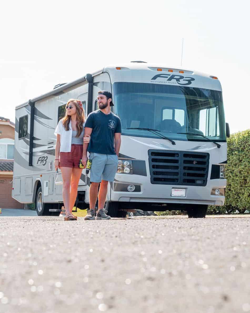 Young couple standing in front of their motorhome
