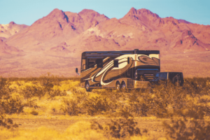 Class A motorhome towing a Jeep in a red desert