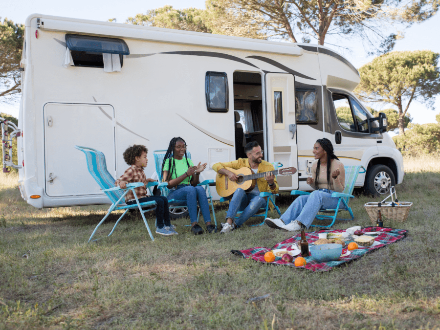 A family hangs out and plays music outside of their RV rental.