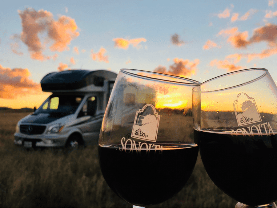 Wine glasses in front of an RV and a gorgeous sunset. 