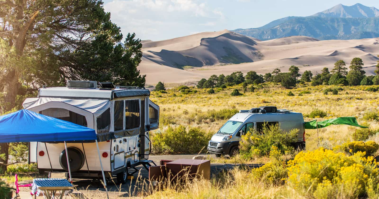 Pop up tent and campervan each setup in their individual campsites with Colorado Sand Dune National Park as the backdrop