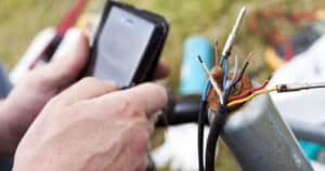 Person using smartphone to search how to repair trailer lights wiring.