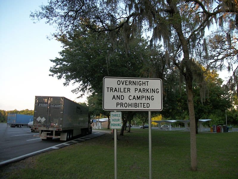 A Rest area sign in Florida stating overnight trailer parking and camping prohibited, 3-hour time limit.