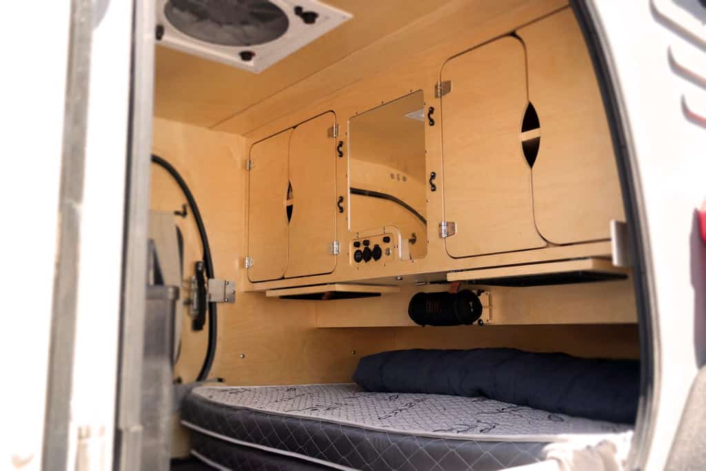 Oregon-Trailer-Interior-TerraDrop-ALPHA: a close-up of the inside of a camper with a mattress in the back of the camper