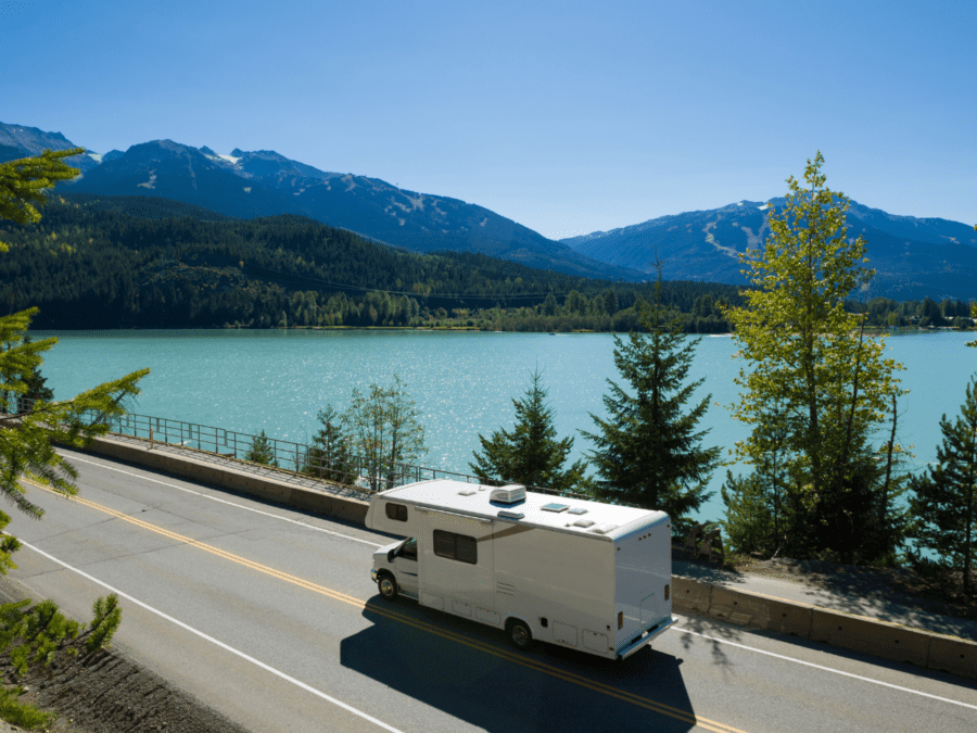 An RV driving near a lake on a sunny spring day.
