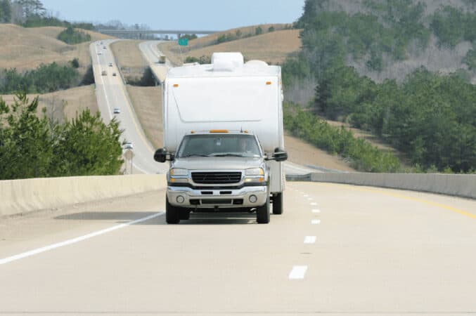 A truck pulls a travel trailer along the highway.
