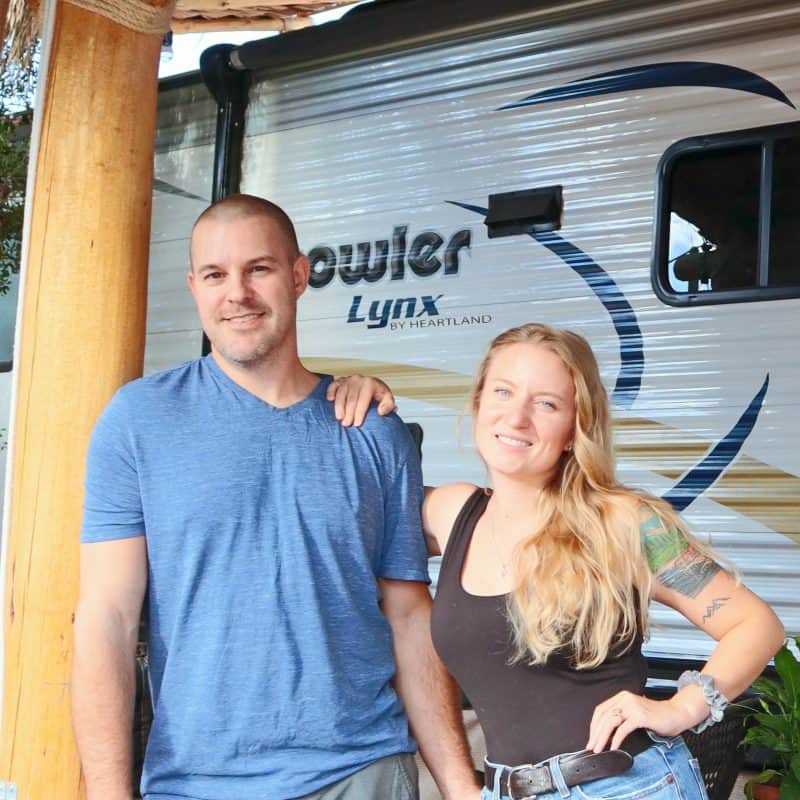 Smiling couple standing outside a Prowler Lynx travel trailer