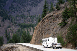 A Class A motorhome towing an SUV on a mountain road