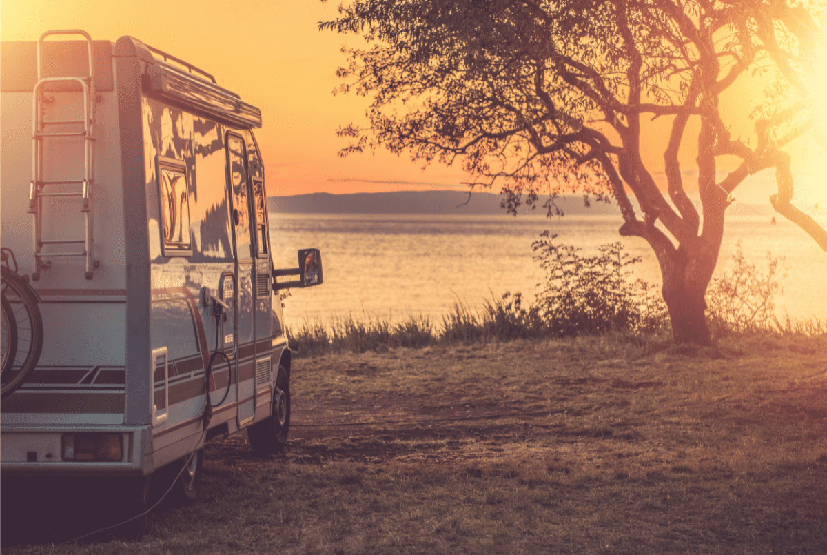 An RV parked by a lake at sunset
