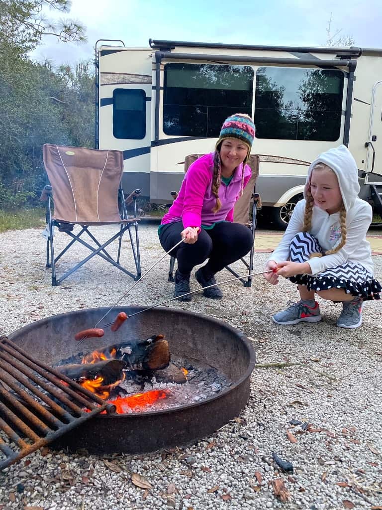 Woman and girl roasting marshmallows in RV campsite while enjoying free camping in Canada.