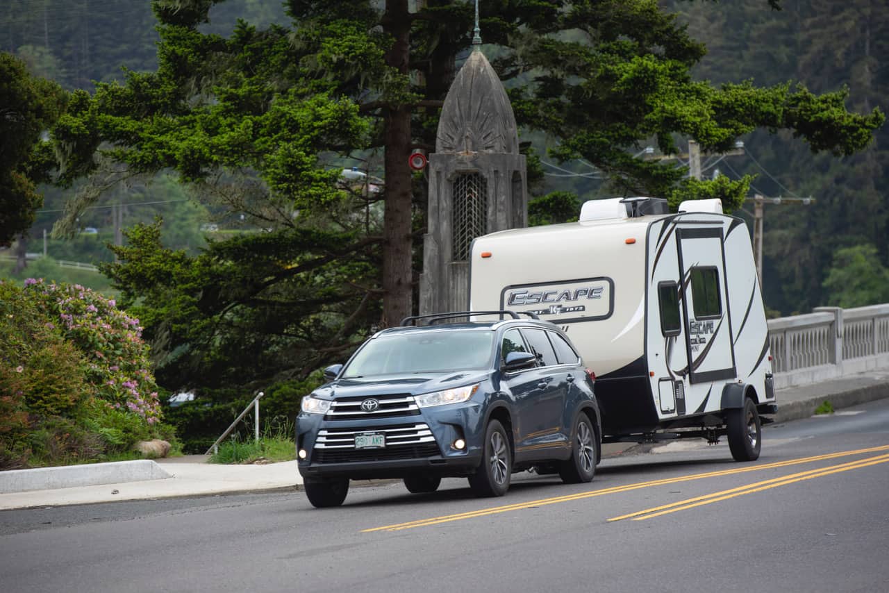 Toyota SUV towing a small travel trailer down the road.