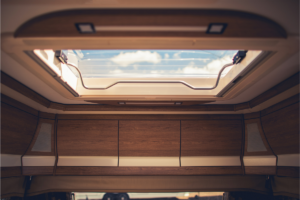 An RV skylight with views of a blue sky and clouds.