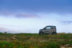 A grey smart fortwo alone in a large field of grass