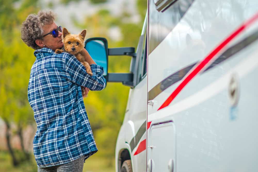 woman taking a break while RVing with her small dog outside of RV