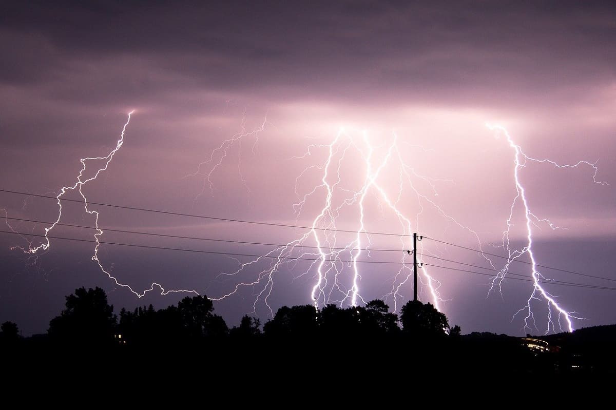 Lightning striking behind power lines at night