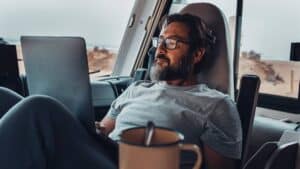 Man lounging in camper van viewing Youtube channels about RVing on his laptop