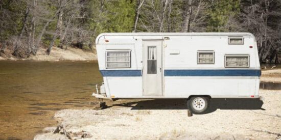 An old RV parked near a river
