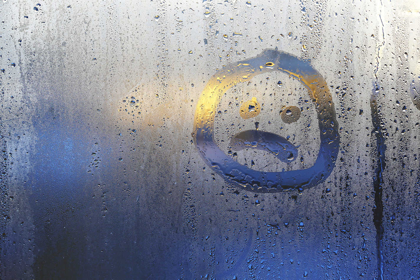 sad face drawn in condensation on a window