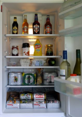 Fridge with the door open and stocked with canned beverages and condiments