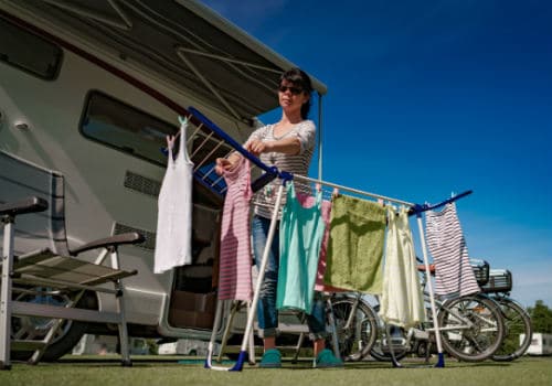 Woman hanging laundry on a drying rack outside of an RV