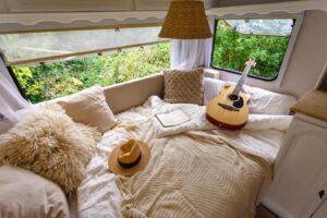 Bed in RV with guitar, hat, and pillows.