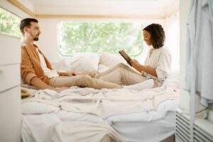 A couple sits in bed in their RV master bedroom