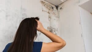 girl found mold in the corner and has hand to head possibly trying to figure out how to go about removing mold