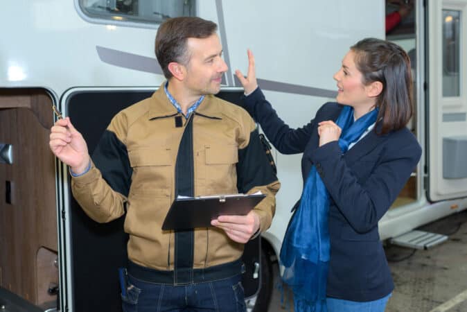 Man and woman standing beside an RV with a clipboars - RV inspection checklist