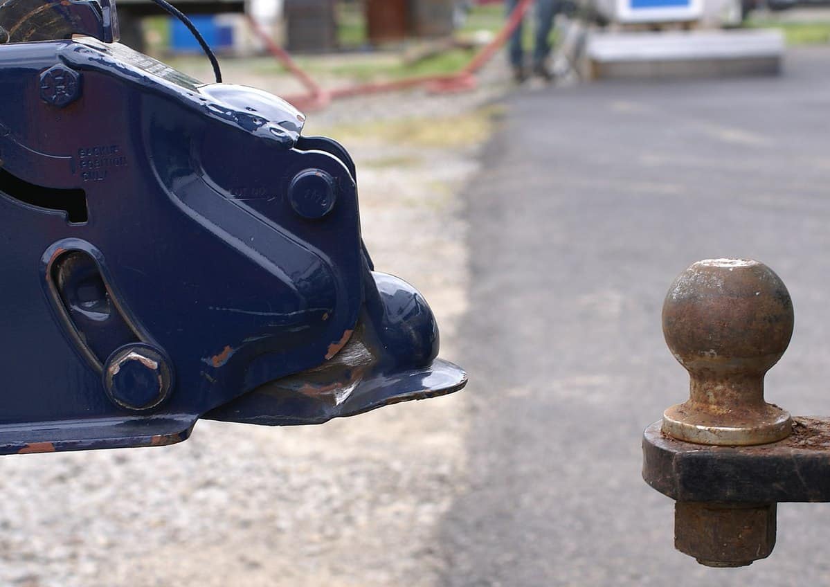 The coupler of a trailer next to a ball hitch, but unattached