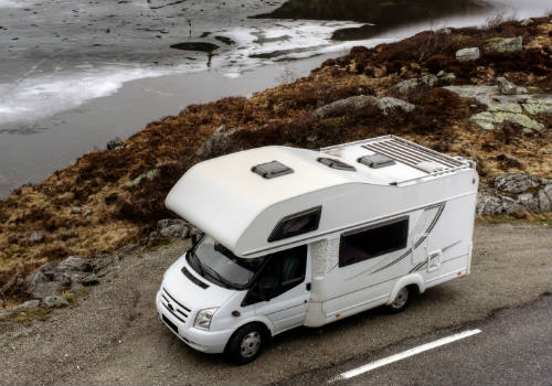Class C RV parked near the ocean with a white roof