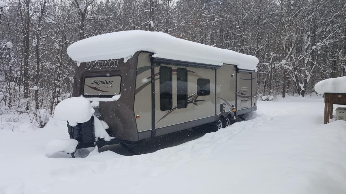 A Rockwood travel trailer in the snow with a couple feet of snow on the roof.